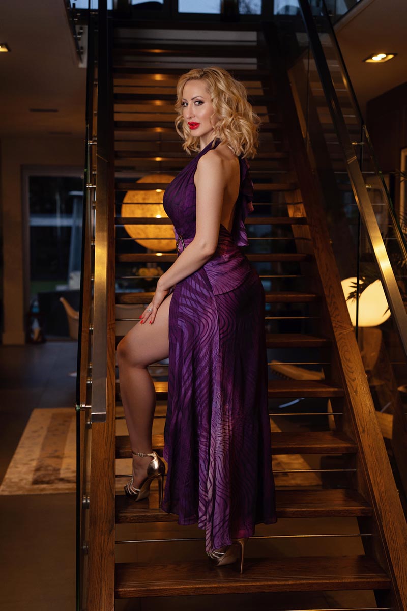 Joelle Monroe auf einer Treppe, sie trägt ein Abendkleid.
